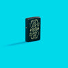Lifestyle image of Zippo Masked Joker Design Black Matte Windproof Lighter standing in a blue scene.