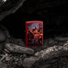 Lifestyle image of Zippo Anne Stokes Fire Dragon Design Red Matte Windproof Lighter standing on rocks set in an alcove.