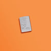Lifestyle image of Zippo Mohawk Skull Design High Polish Chrome Windproof Lighter in an orange scene.