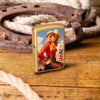 Lifestyle image of Zippo Rancher Design Regular Street Brass Windproof Lighter standing on a wooden table with a horseshoe and rope.
