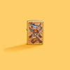 Lifestyle image of Zippo Guy Harvey Regular Street Brass Windproof Lighter on a yellow background.