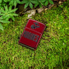 Lifestyle image of Zippo U.S. Marine Corps Candy Apple Windproof Lighter laying on a bed of grass.