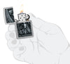 Zippo Grim Beauty Design Street Chrome Windproof Lighter lit in hand.